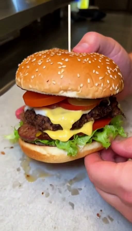Preview of First bite of a stacked burger, close-up